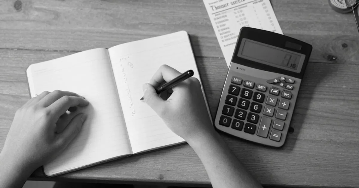 Manos haciendo cálculos en una libreta junto a una calculadora
